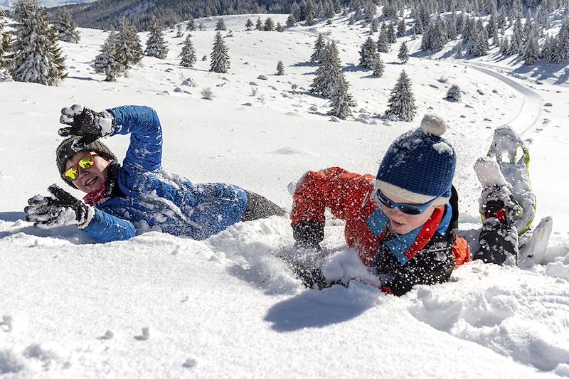 Jeunes garçons jouant dans la neige en raquettes - France