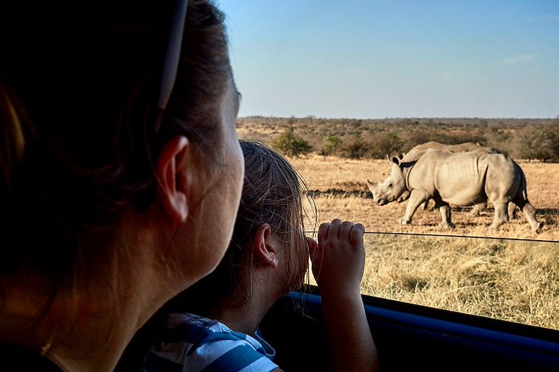 Mère et fille observant des rhinocéros à travers la fenêtre d'une voiture - Afrique du Sud