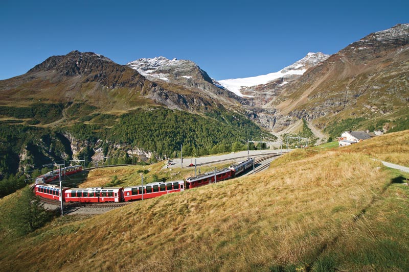 Le train Bernina Express serpentant dans les montagnes suisses &agrave; Alp Gr&uuml;m  