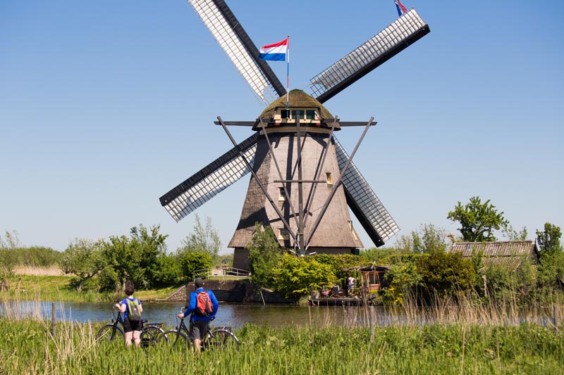 Couple de cyclistes face &agrave; un moulin &agrave; vent &agrave; Kinderdijik - Pays-Bas