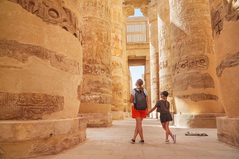 Une m&egrave;re et sa fille touristes entre les colonnes du temple de Karnac &agrave; Louxor - &Eacute;gypte &copy; Igor/stockadobe.com 