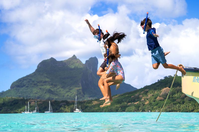 Snorkeling en famille à Bora-Bora en Polynésie française © Tahiti Tourisme Famille avec masque et tuba sautant dans la mer à Bora-Bora en Polynésie