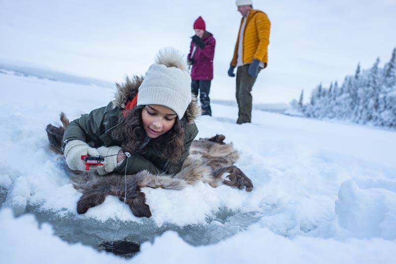 Pêche blanche en famille à Namdalem en Norvège © Marius Rua/ Buckethaus/Explore-Trondelag Petite fille pêchant sous la glace à Namdalem en Norvège