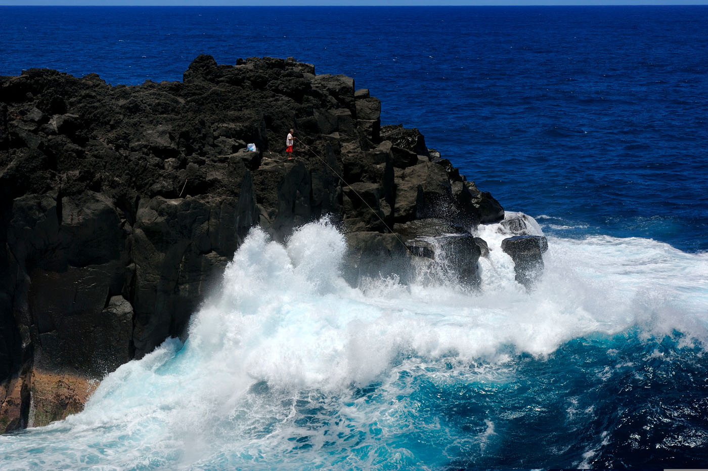 Pêcheur sur un rocher et les remous au cap Méchant dans le Sud sauvage à la Réunion